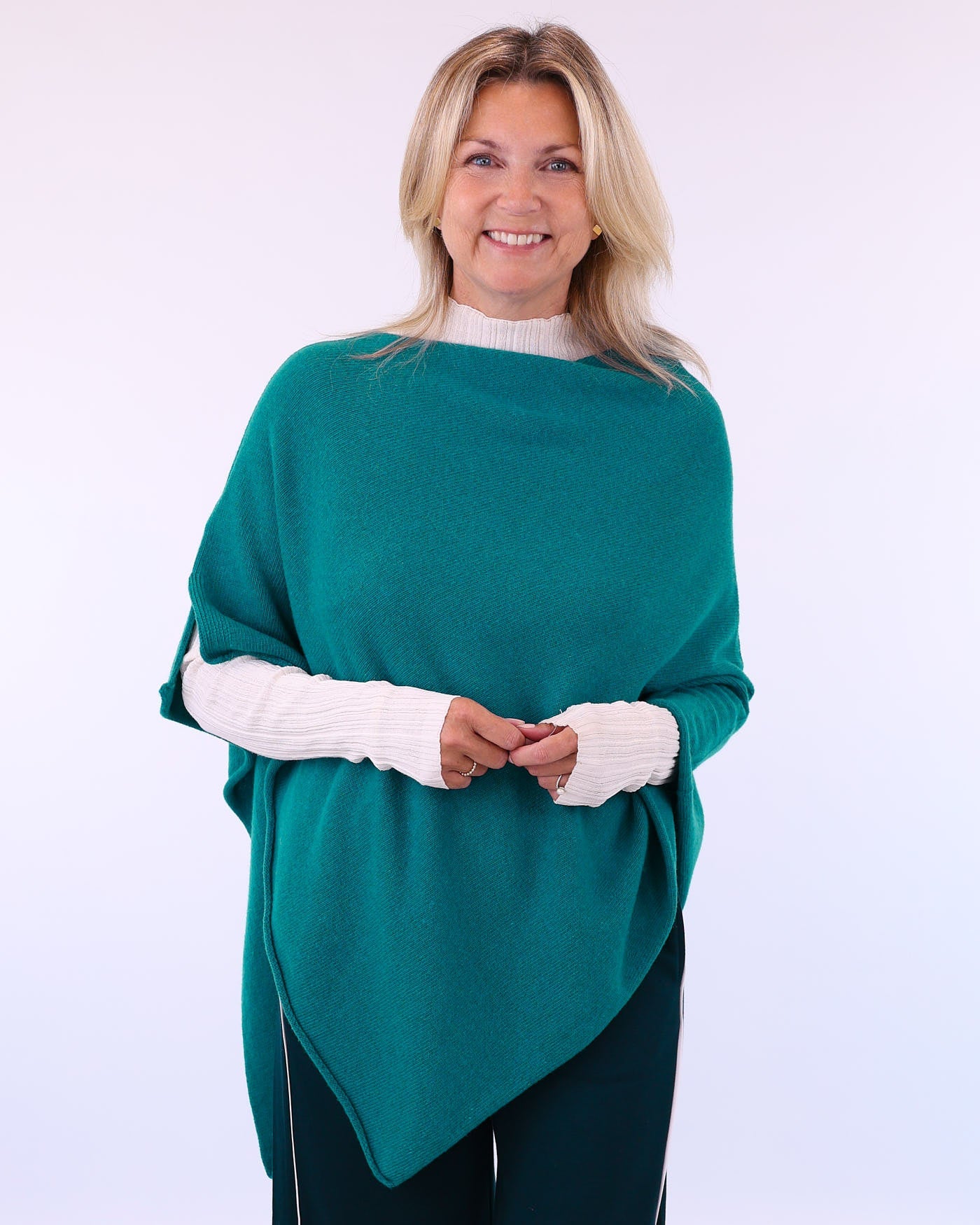Women's cashmere blend poncho in teal blue, worn with long sleeve cream T-shirt, made in Italy
